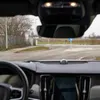 View from inside a car looking out at a roundabout with a blue directional sign. Náhled obrázku produktu