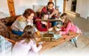 A family is playing a ring toss game around a wooden table in a living room. Náhled obrázku produktu