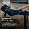 A person wearing a black compression sleeve on their arm while working at a computer. Podgląd zdjęcia produktu