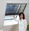 A woman is adjusting a pleated blind on a skylight window. Produktbild-Vorschau