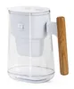 A clear water pitcher with a white filter and a wooden handle. Produktbild-Vorschau