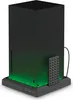 A black docking station with green LED lighting, designed for an Xbox console, is shown on a white background. A black remote control is attached to the side of the docking station. Náhľad obrázku produktu