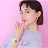 A young woman wearing a light blue sweater and a white watch, posing against a pink background. Anteprima dell’immagine prodotto