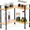 A two-tiered corner shelf unit made of wood and black metal, holding various kitchen items like spice jars, pepper grinders, and a bottle of olive oil. Anteprima dell’immagine prodotto