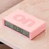 A pink digital alarm clock with the word "on" embossed on its lid, placed on a marble-like surface. Náhled obrázku produktu
