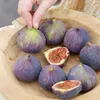 A hand is picking up a fig from a wooden bowl filled with figs. Produktbild-Vorschau