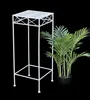A white metal plant stand next to a potted green plant. Anteprima dell’immagine prodotto