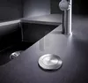 A close-up shot of a modern kitchen sink area, focusing on a sink drain and a faucet. Podgląd zdjęcia produktu