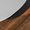 Three round placemats in different colors (gray, black, and brown) are layered on top of each other on a wooden surface. The placemats have the brand name 'miqio' embossed on them. Produktbild-Vorschau