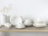 A collection of white porcelain dinnerware, including plates, bowls, and cups, arranged on a wooden shelf against a white background. Náhľad obrázku produktu