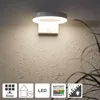 A solar-powered wall light mounted on a textured wall, with icons indicating its features. Produktbild-Vorschau
