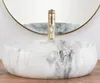 A marble sink with a gold faucet in front of a mirror. Produktbild-Vorschau