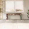 A rustic wooden bench sits on a tiled patio in front of a large window with white blinds. Voir les images du produit