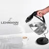 A hand is pouring hot water from a glass electric kettle into a white mug, with steam rising. Voir les images du produit
