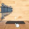 A set of wrenches mounted on a rack against a wooden background, with a cursor pointing to a black rectangular object on the floor. Produktbild-Vorschau