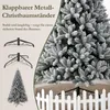 A flocked artificial Christmas tree with its metal stand and a small white picket fence. Produktbild-Vorschau