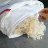 A hand is shown closing a zipper on a pillow filled with fluffy material and wood shavings. Produktbild-Vorschau