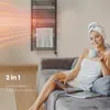 A woman wrapped in towels sits on a sofa with a magazine and a mug, next to a heated towel rack. Podgląd zdjęcia produktu