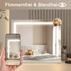 A bedroom scene with a vanity mirror and a hand holding a smartphone showing a reflection of the mirror. Anteprima dell’immagine prodotto