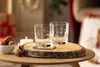 Two glasses on a wooden coaster with a candle and walnuts. Produktbild-Vorschau