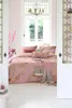 A bedroom scene with a bed dressed in pink floral bedding, a throw blanket, and pillows, viewed through an open doorway with stained glass. Produktbild-Vorschau