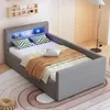 A grey upholstered bed with LED lighting in the headboard, set up in a bedroom with a rug and a floor lamp. Produktbild-Vorschau