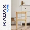 A wooden stool is placed in a room with a dresser and a basket. Voir les images du produit