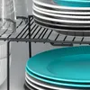 A close-up view of a black metal shelf unit holding stacks of plates and glasses. Anteprima dell’immagine prodotto