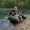 A man is fishing in an inflatable boat on a lake surrounded by trees. Podgląd zdjęcia produktu