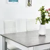 A dining set with white chairs and a gray table with a floral arrangement. Voir les images du produit