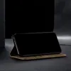 A smartphone in a khaki flip case is propped up on a dark surface, with a black background. Produktbild-Vorschau
