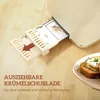 A close-up of a toaster's crumb tray being pulled out, with a piece of toast on a plate in the background. Produktbild-Vorschau