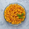 A clear overhead shot of uncooked elbow macaroni in a glass bowl, with a sprig of basil on top. Produktbild-Vorschau