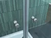 A close-up view of a shower cabin with tiled walls and chrome fixtures. Produktbild-Vorschau