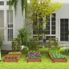 A garden scene with raised garden beds in front of a white house. Voir les images du produit