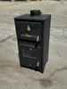 A black wood-burning stove with glass doors sits on a concrete surface. Produktbild-Vorschau