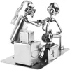 A metal figurine of two people, one appearing to be a tattoo artist and the other a client, with tattoo equipment and boxes. Podgląd zdjęcia produktu