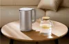 A silver electric kettle and a glass pitcher with lemon slices are placed on a wooden coffee table in front of a sofa. Náhľad obrázku produktu