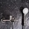 A close-up shot of a shower faucet and handheld showerhead against a dark, textured wall. Produktbild-Vorschau