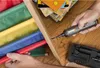 A person is using a cordless electric screwdriver to assemble a wooden shelf with colorful fabric dividers. Produktbild-Vorschau