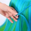 A hand is shown attaching a blue hair extension to a wig with blue and green strands. Náhľad obrázku produktu