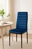 A blue velvet dining chair is shown in a well-lit room with a round table and a window in the background. Produktbild-Vorschau