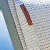 A close-up of a woven fabric with a brown leather tag attached. Produktbild-Vorschau
