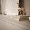 A close-up shot of decorative items on a shelf, including a metallic deer figurine and books. Produktbild-Vorschau