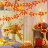 A cozy indoor scene with autumn-themed decorations, including string lights shaped like maple leaves and pumpkins, a lit candle, and a mug. Náhled obrázku produktu