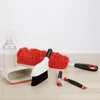 A collection of cleaning tools, including a spray bottle, dustpan, brushes, and a duster, arranged on a wooden surface against a white background. Anteprima dell’immagine prodotto