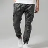 A person wearing camouflage cargo pants and white sneakers, shown from the waist down. Produktbild-Vorschau