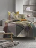 A bed with geometric patterned bedding is shown in a room with minimalist decor. Produktbild-Vorschau