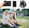 Two women sitting on grass in a park, with a product laid out on the ground. Produktbild-Vorschau