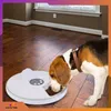 A beagle dog is eating from an automatic pet feeder on a wooden floor in a room with brown walls and a window. Anteprima dell’immagine prodotto